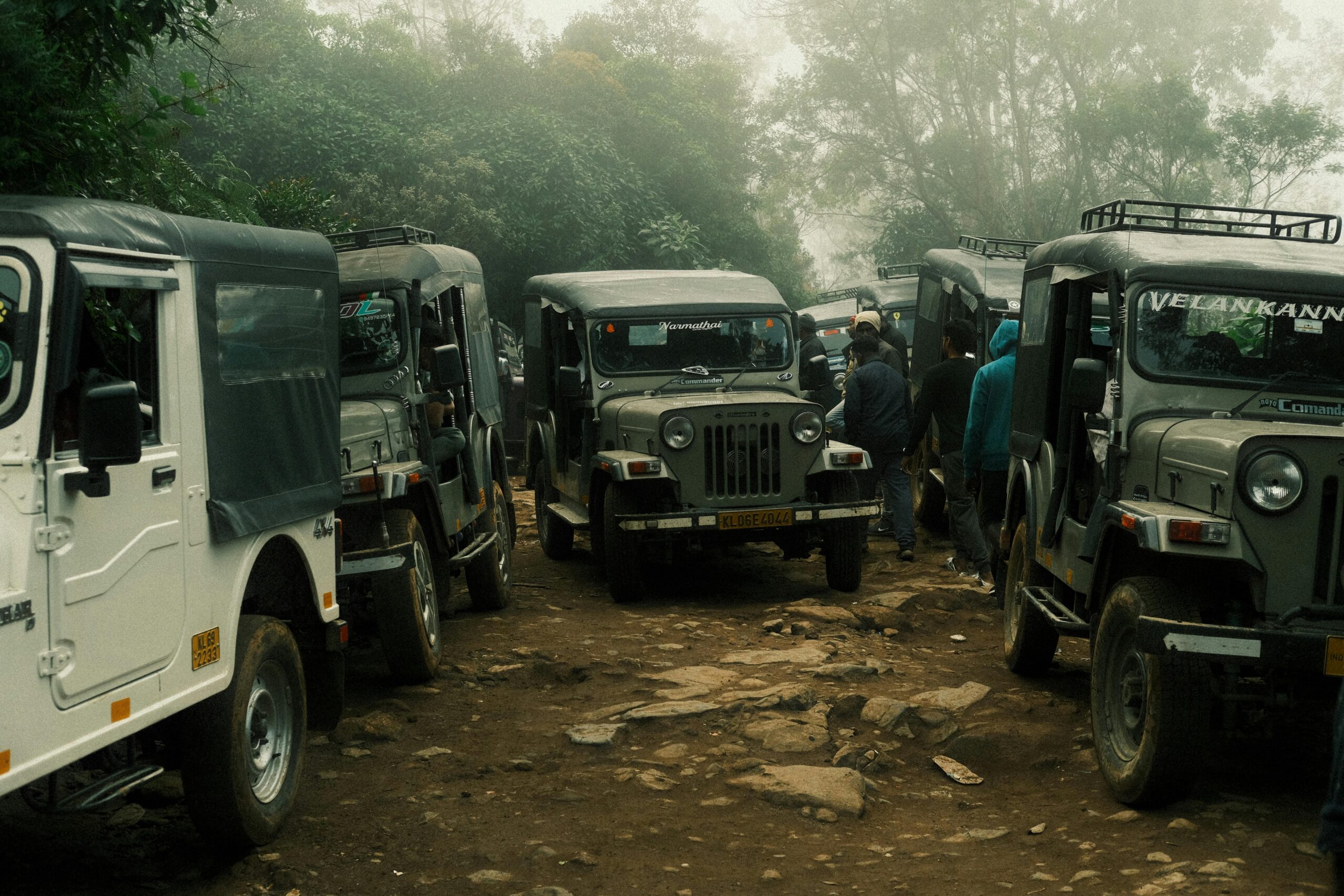 A line of rugged jeeps on a misty forest trail in Idukki, Kerala, India.